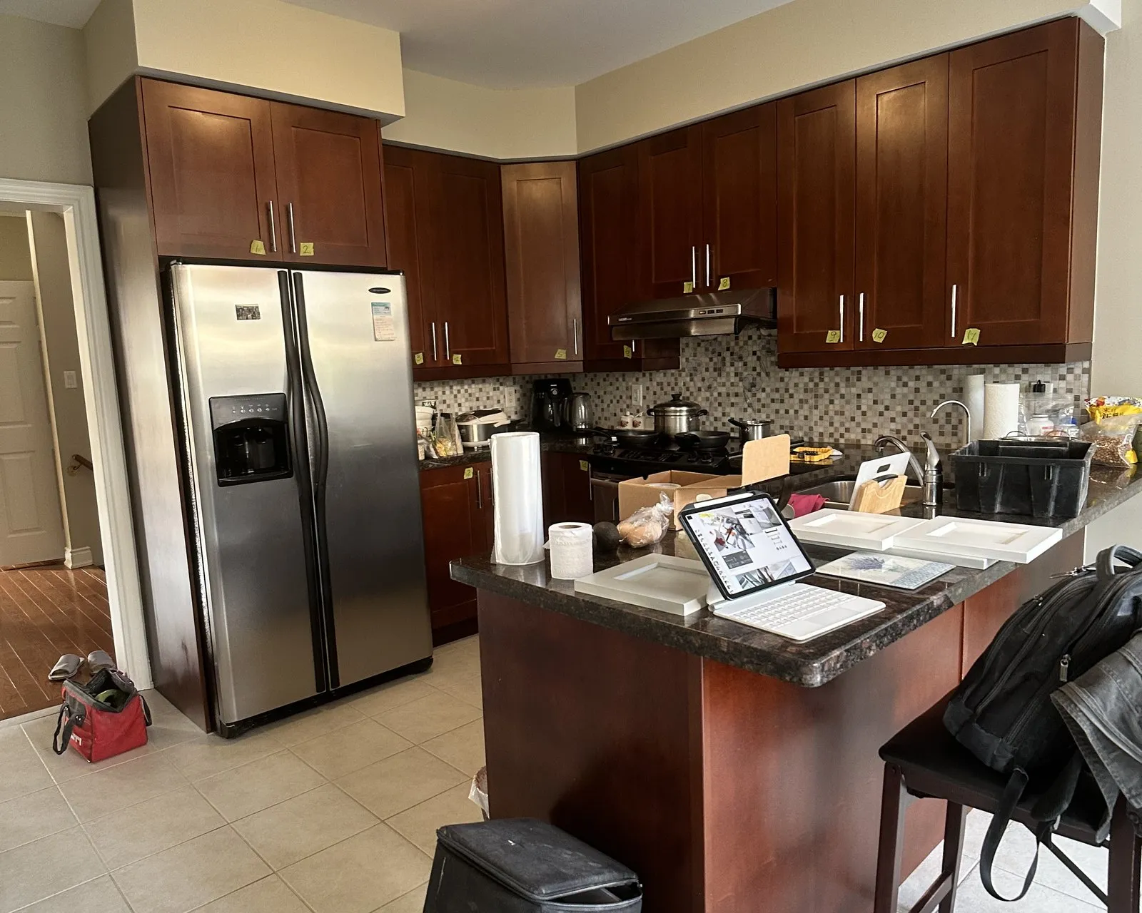Before — A kitchen before and after — dark cherry fronts replaced with white, on the same boxes, with the granite, mosaic backsplash and tile floor all kept