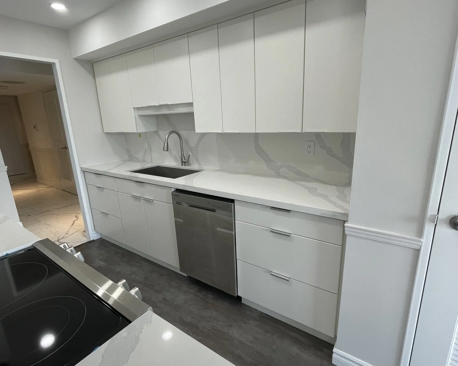 A refaced galley kitchen finished in white gloss, the run reading as one continuous surface with no seams at the frames