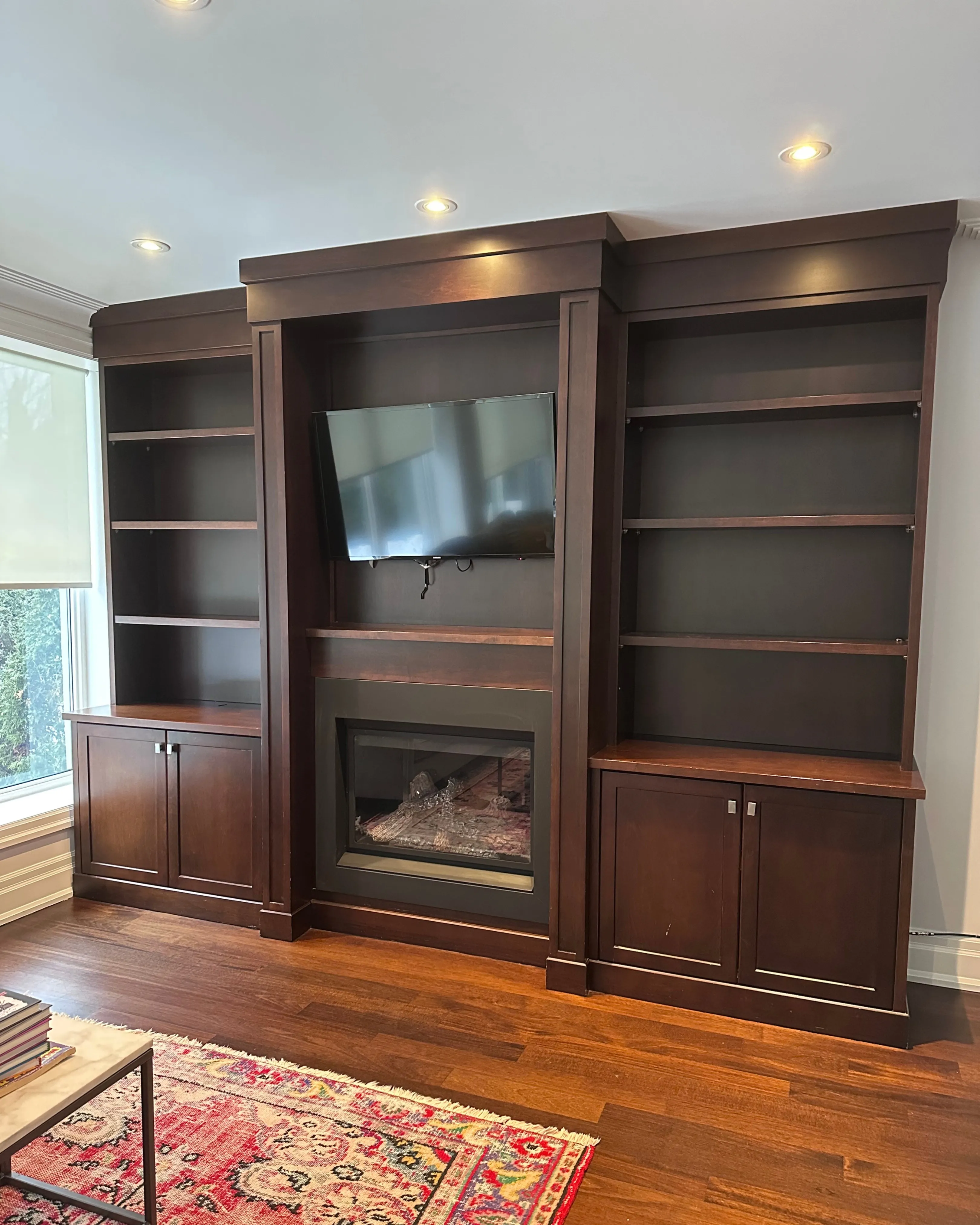Before — A built-in shelving unit around a fireplace, before in dark espresso wood and after painted crisp white, the same room and the same angle