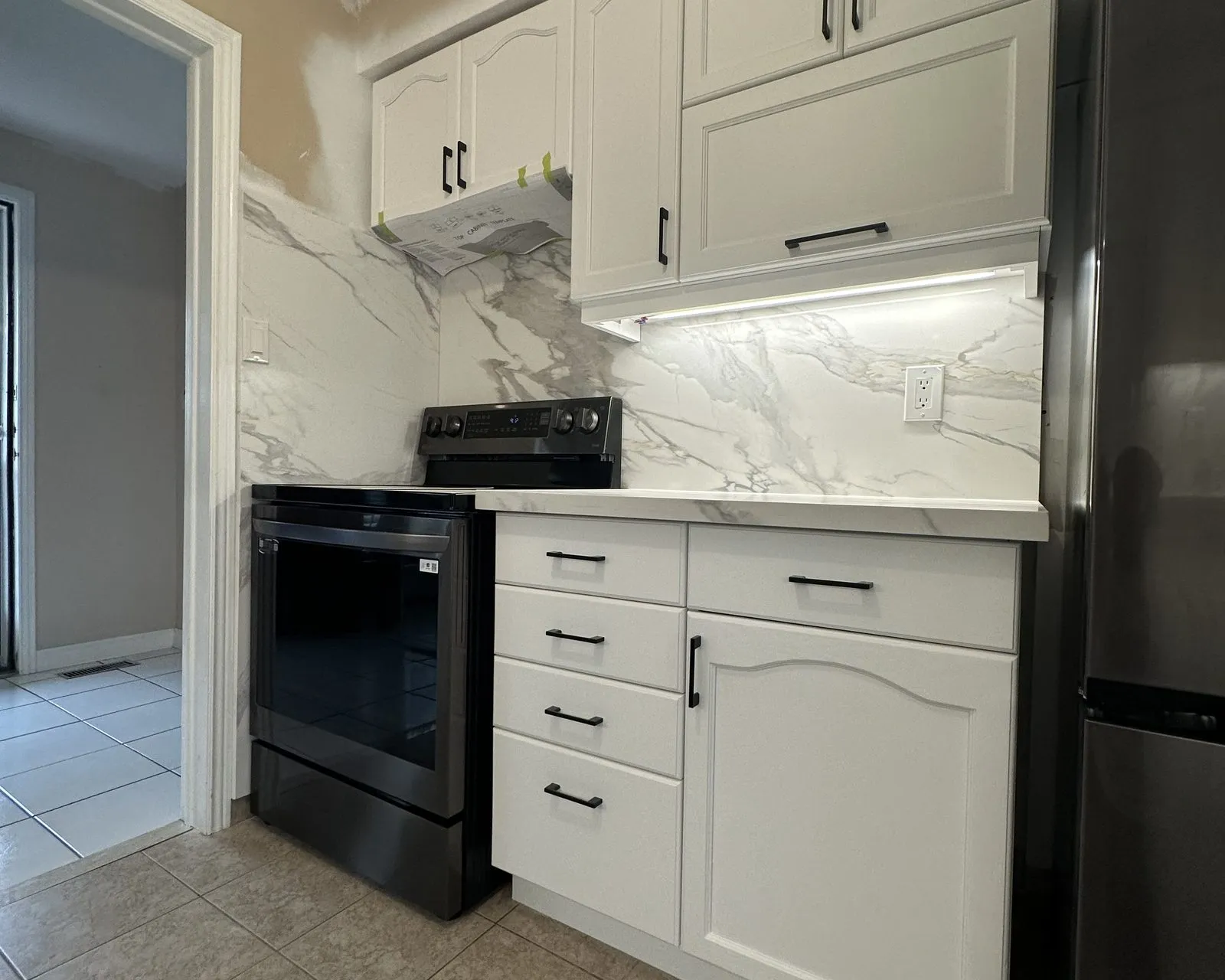 After — Backsplash installation in Bronte Creek, Oakville — diamond-set travertine tile replaced with a full-height quartz slab run continuously behind the counter