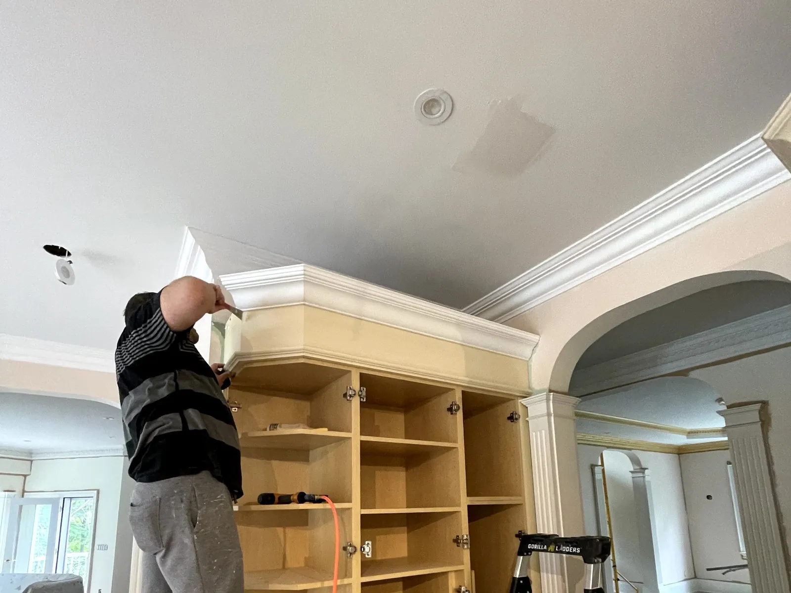 Crown moulding being scribed and fitted to a built-in, cut on site rather than ordered to a drawing