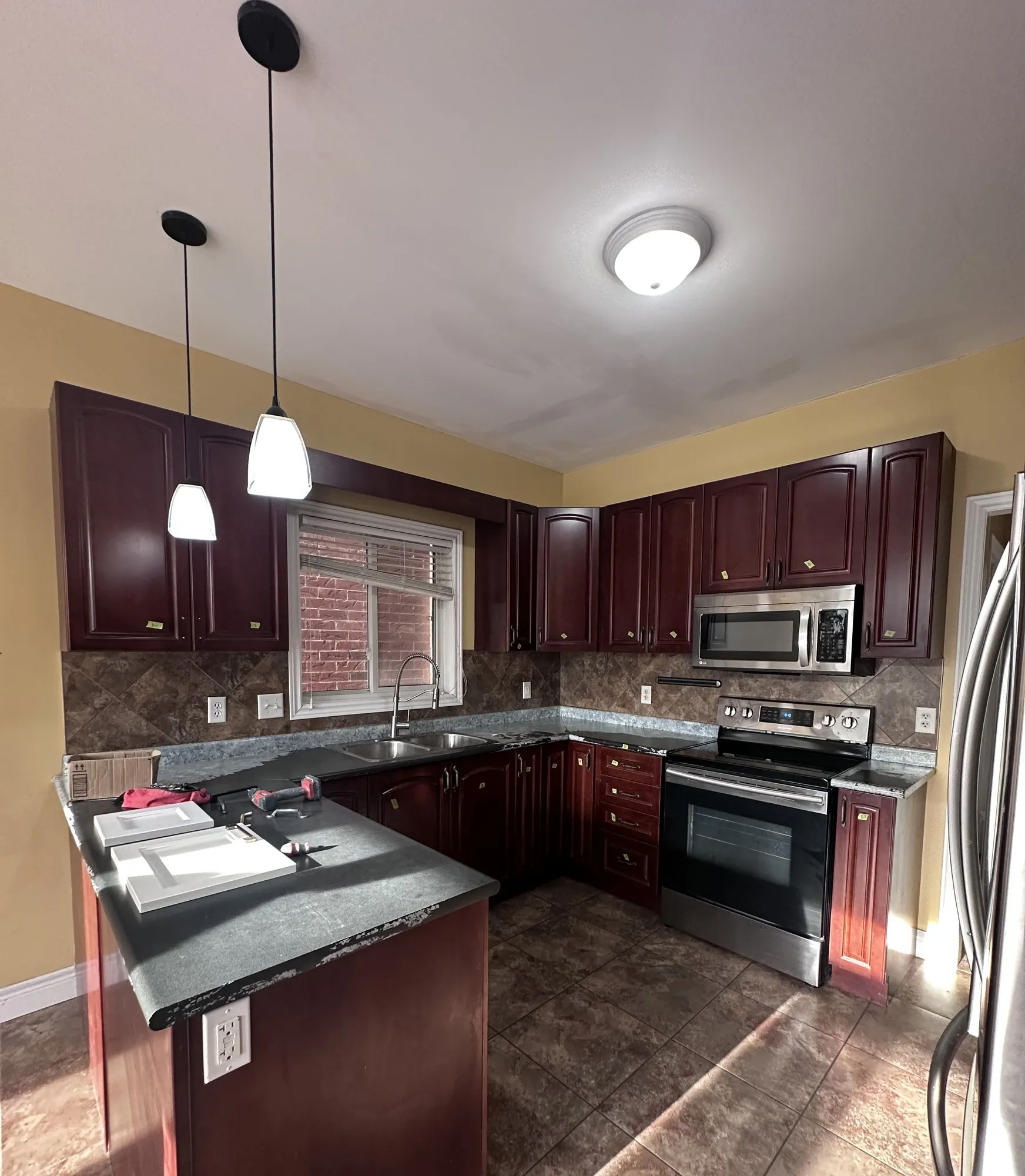 The original kitchen in dark cherry — every door, frame and gable in the same near-black stain, with dark counters and a stone-look backsplash