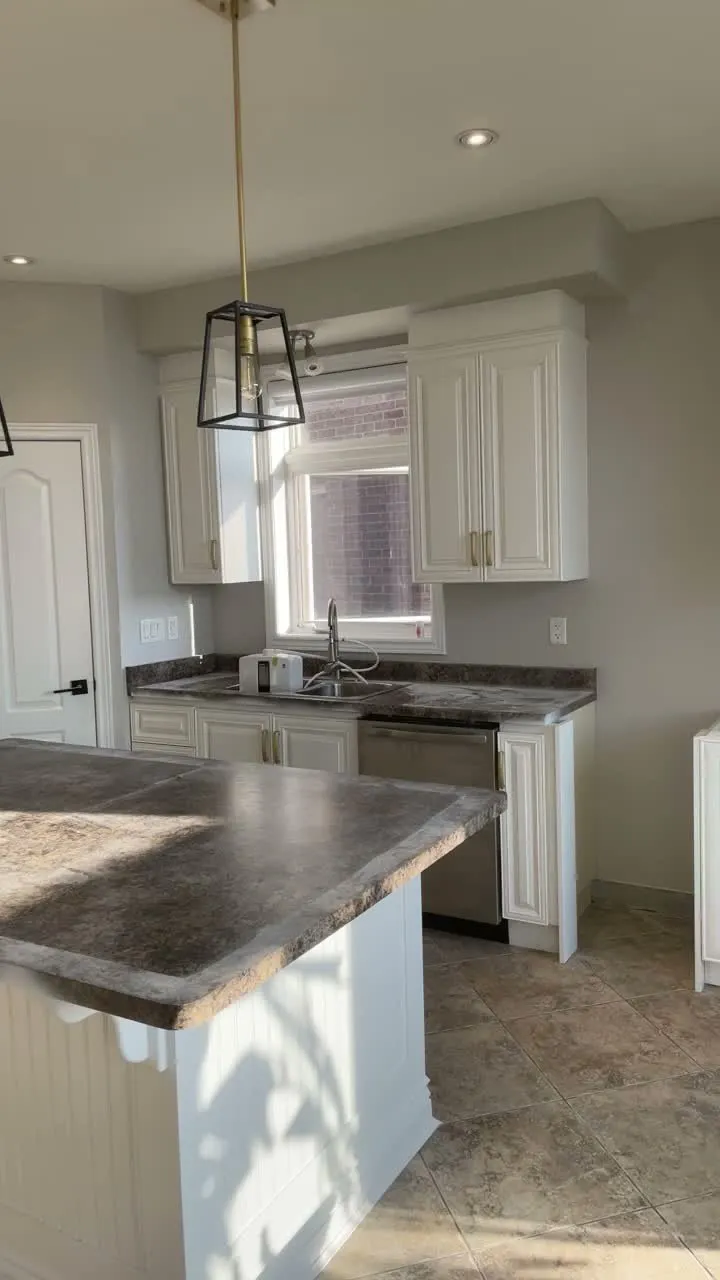 A walk through the finished Stoney Creek kitchen — white cabinetry with glass-fronted uppers and a beadboard island, the original speckled counters and tile floor kept