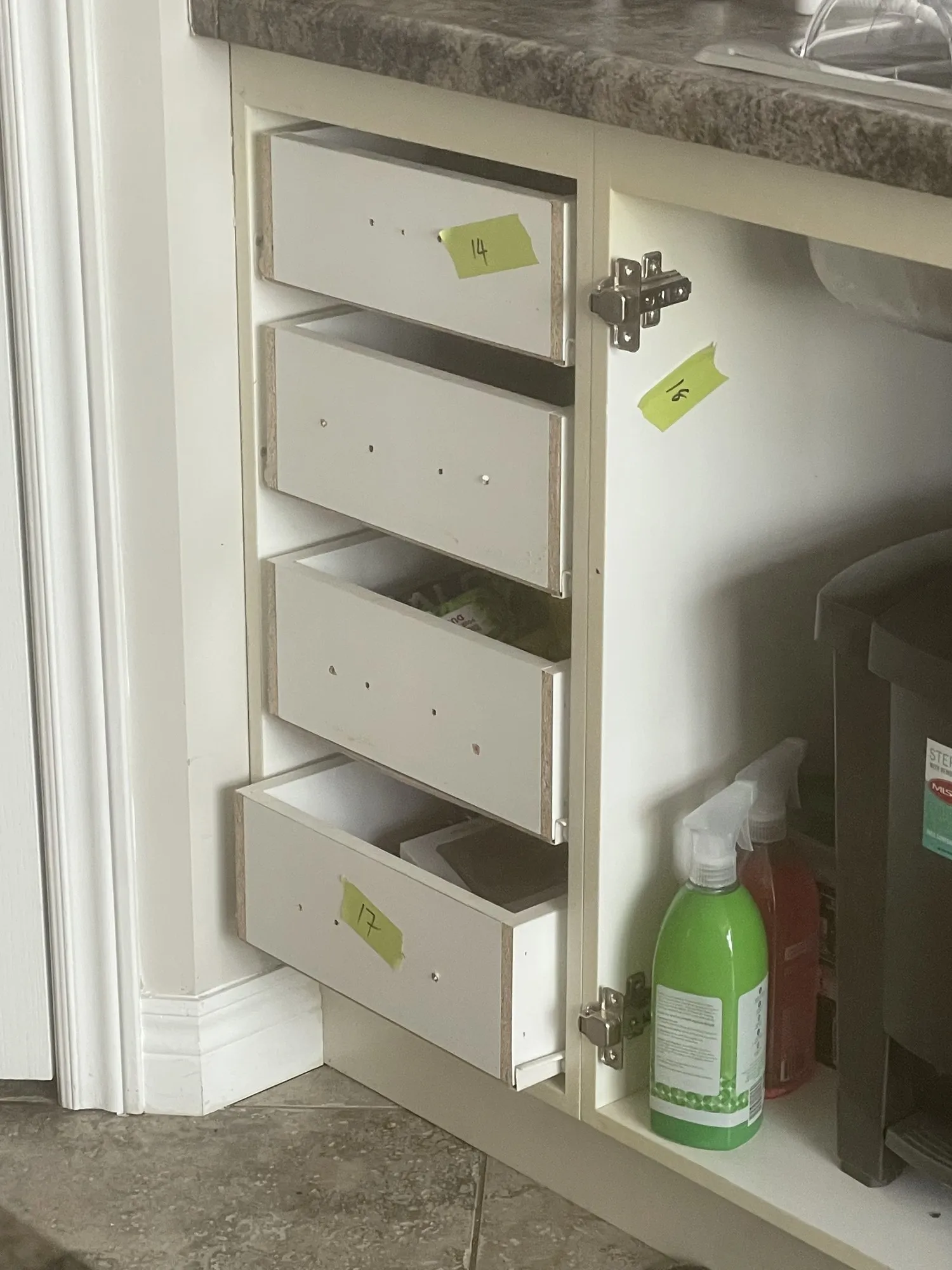 Drawer boxes pulled out of a cabinet with small yellow numbered tags stuck to each one before removal