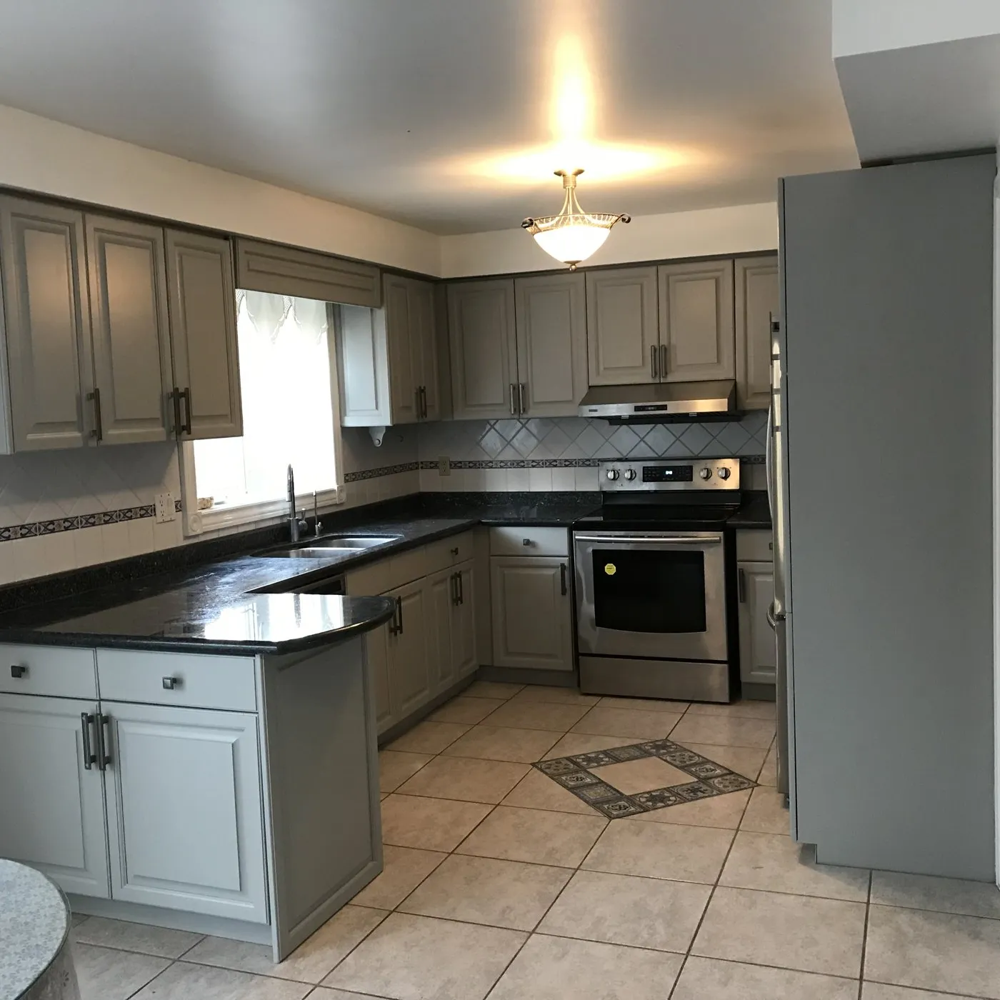 After — Colour consultation in Winston Park, Oakville — golden oak taken to a soft grey, the counters and backsplash kept