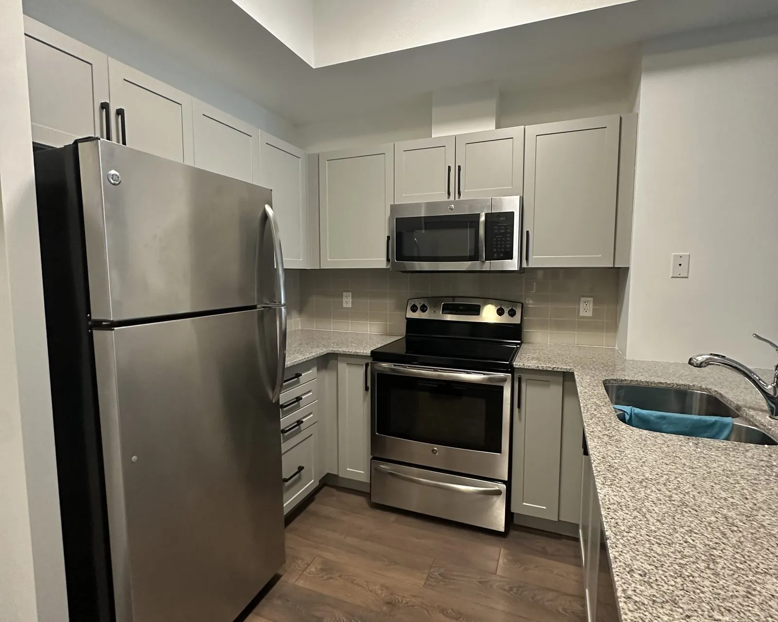 After — Cabinet door replacement in Kerr Village, Oakville — espresso thermofoil doors on the original boxes, then new cashmere grey doors hung on the same carcases
