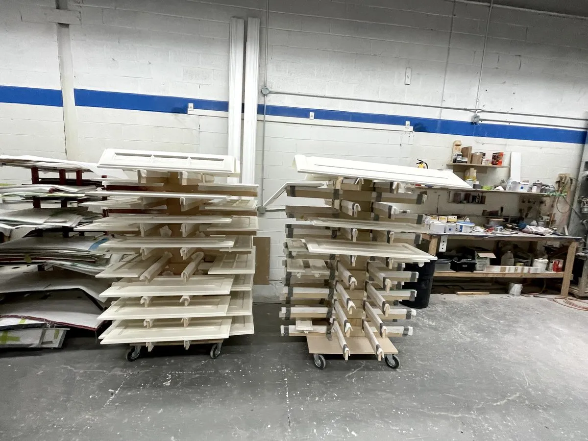 Finished cabinet doors racked on rolling carts in the shop, made to measure and ready for the booth
