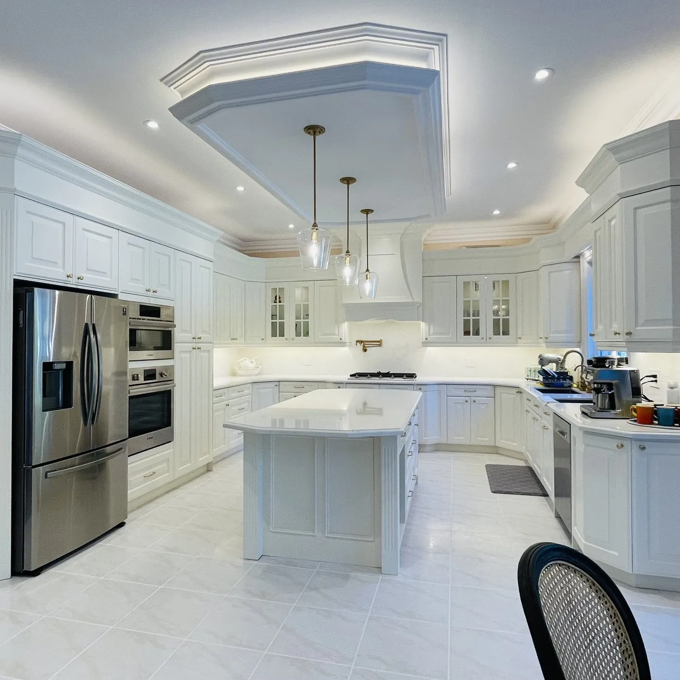 After — Custom cabinetry in Eastlake, Oakville — a kitchen mid-install in primed carcases, then finished in white with a fitted hood surround and coffered ceiling