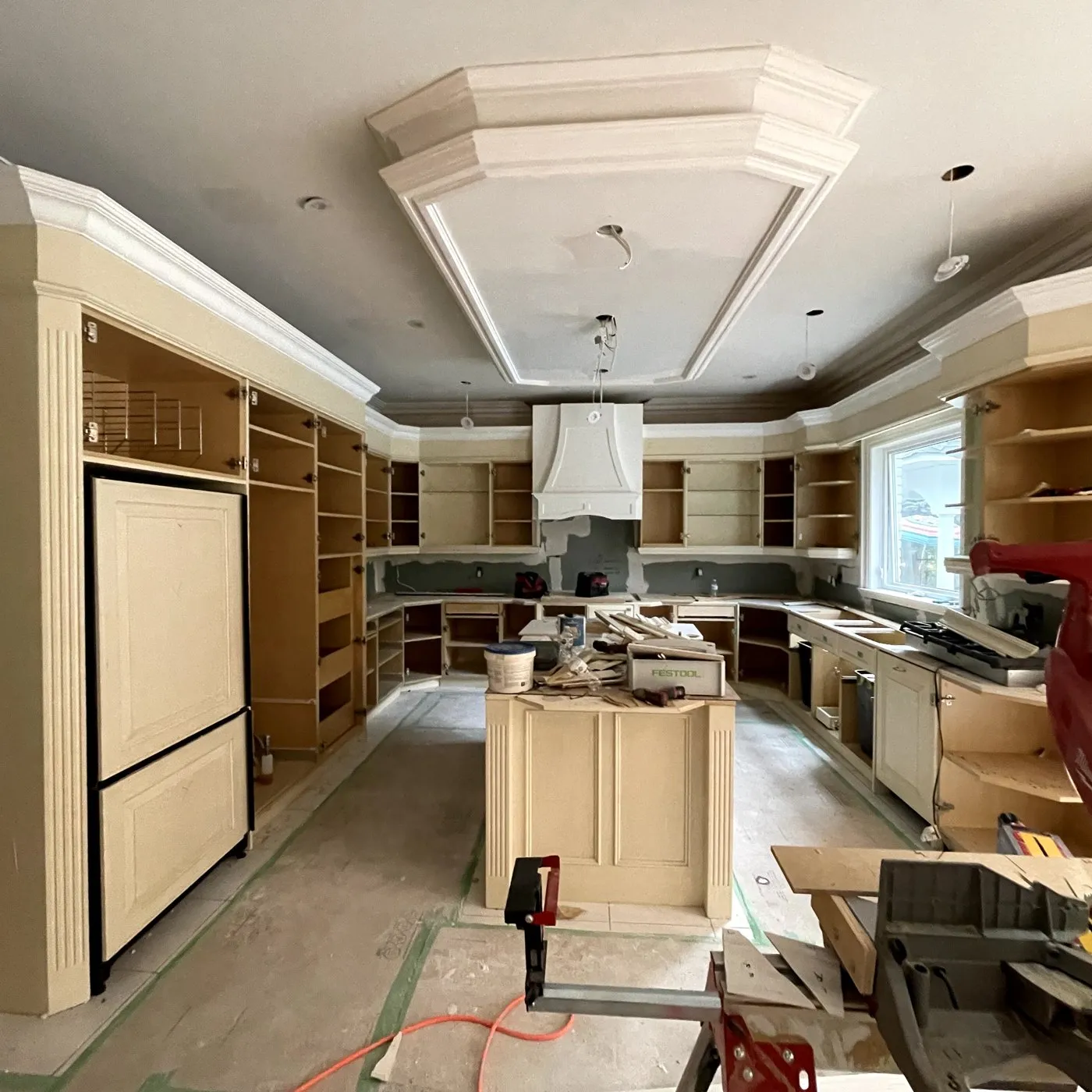 Before — Custom cabinetry in Eastlake, Oakville — a kitchen mid-install in primed carcases, then finished in white with a fitted hood surround and coffered ceiling