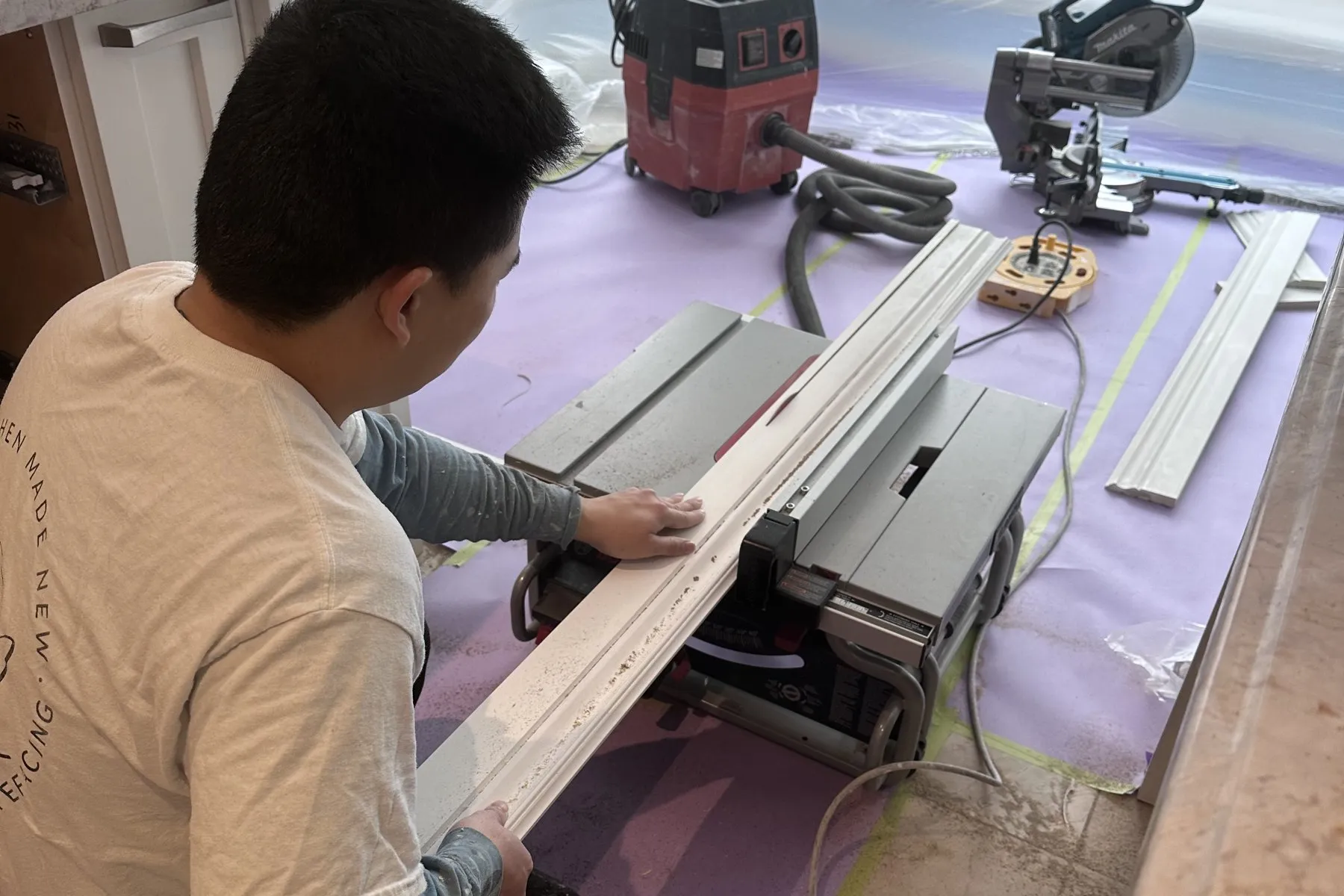 Millwork cut on site in an Oakville kitchen — a length of moulding run through a table saw under containment, rather than ordered to a drawing