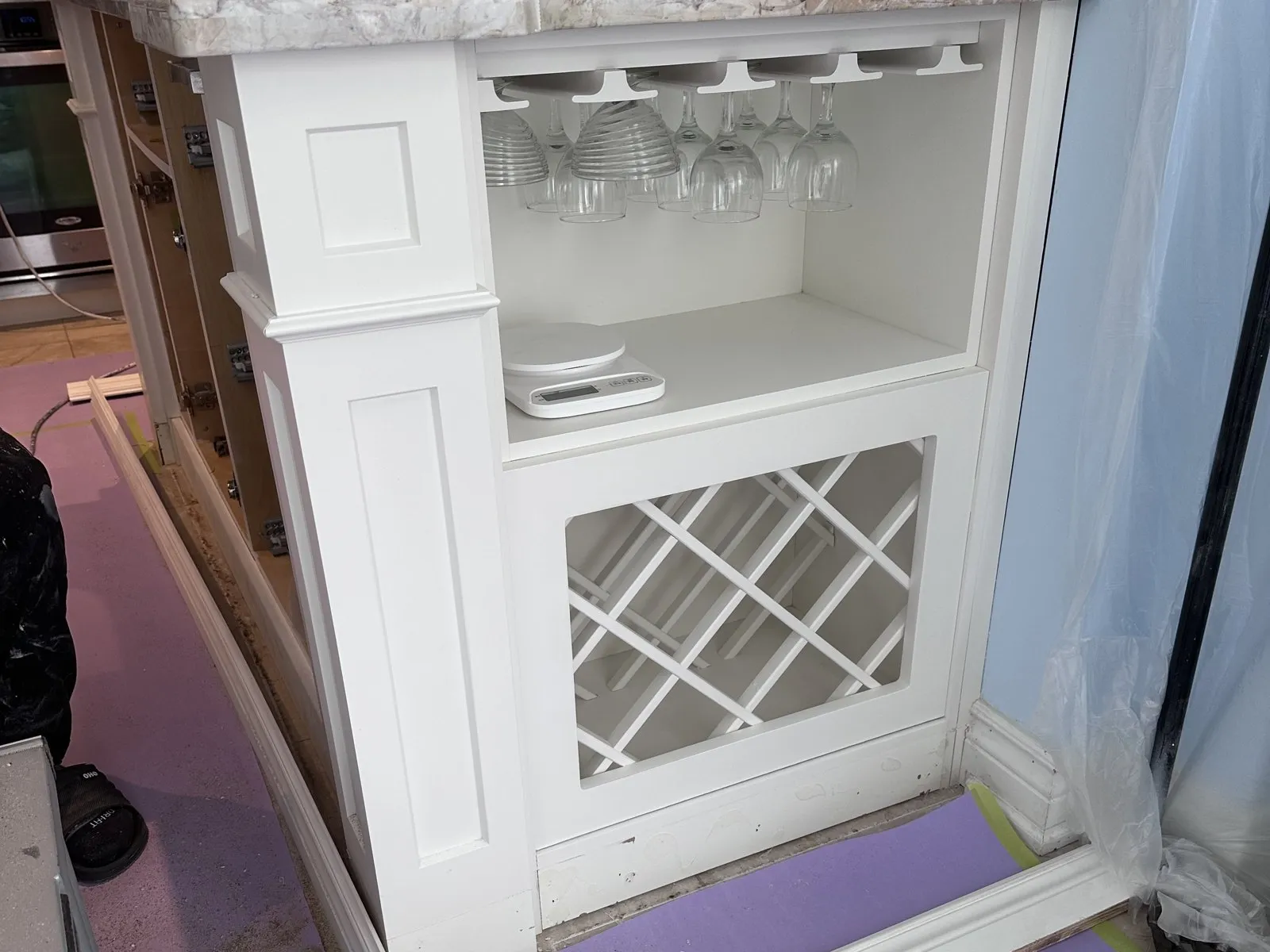 A built-in wine unit going in, its baseboard scribed and cut to meet the floor it sits on