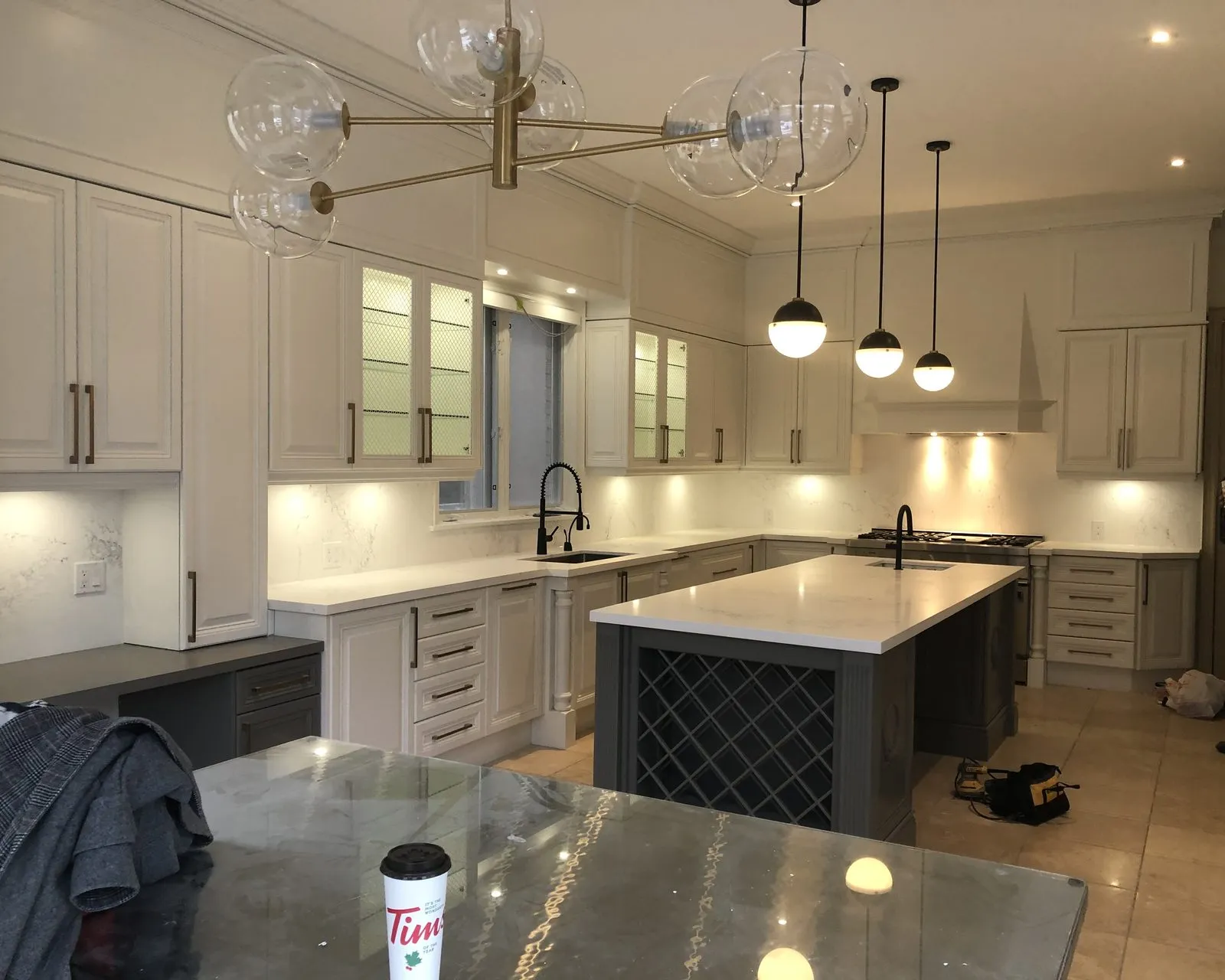 After — Full kitchen design in Southeast Oakville — a traditional maple kitchen planned and rebuilt in white, the island moved and finished in charcoal with its wine lattice kept