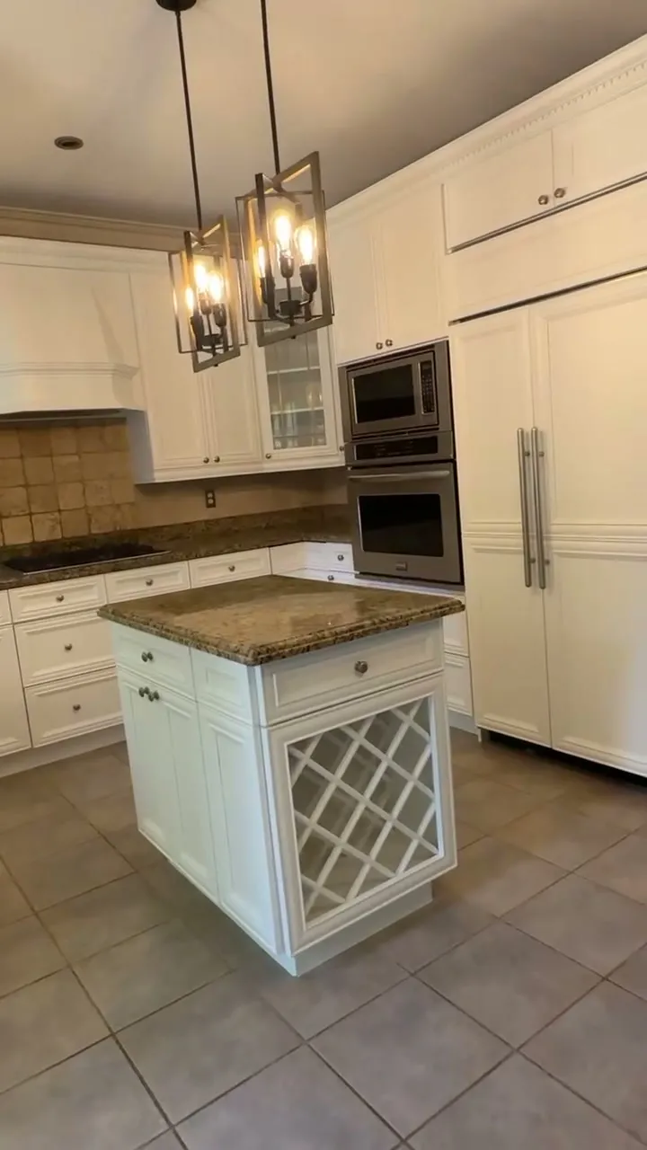 The finished Clearview kitchen — antiqued cream cabinetry sprayed bright white, with the original granite, tiled backsplash and lattice wine island all kept