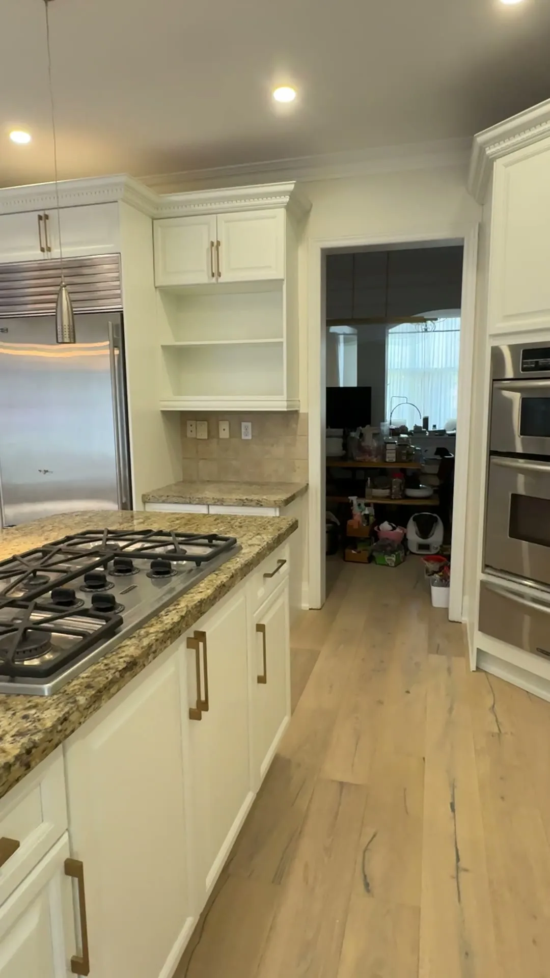 The finished Joshua Creek kitchen — dark espresso cabinetry sprayed Cloud White around a large island, the granite counters and wood floor kept