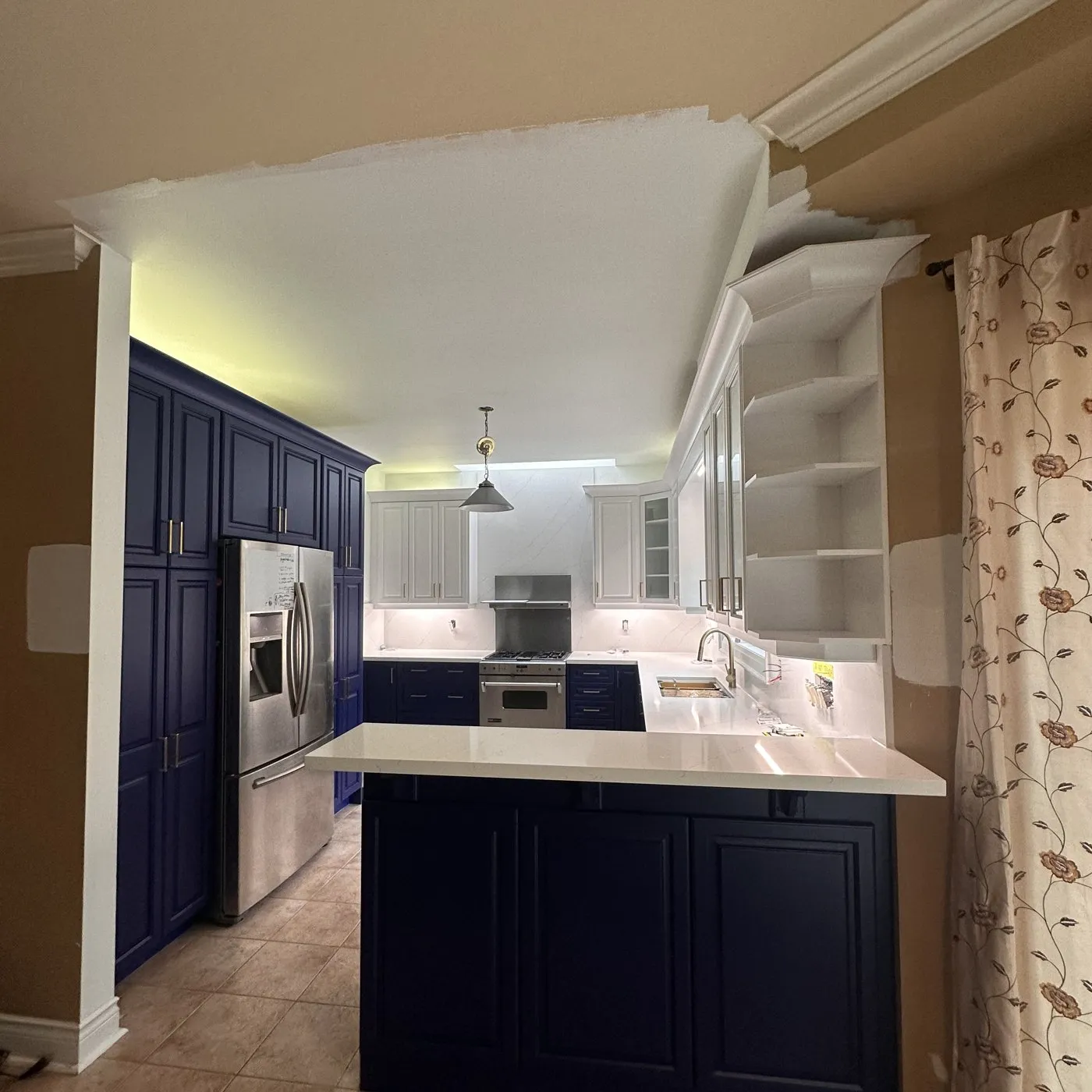 After — Kitchen cabinet painting in Kerr Village, Oakville — maple cabinetry sprayed navy below and white above, the boxes and layout unchanged
