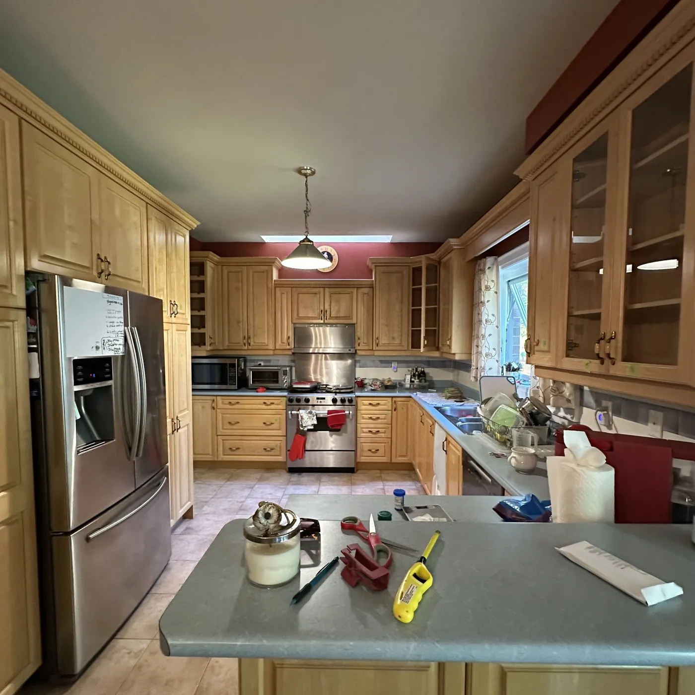 Before — Kitchen cabinet painting in Kerr Village, Oakville — maple cabinetry sprayed navy below and white above, the boxes and layout unchanged