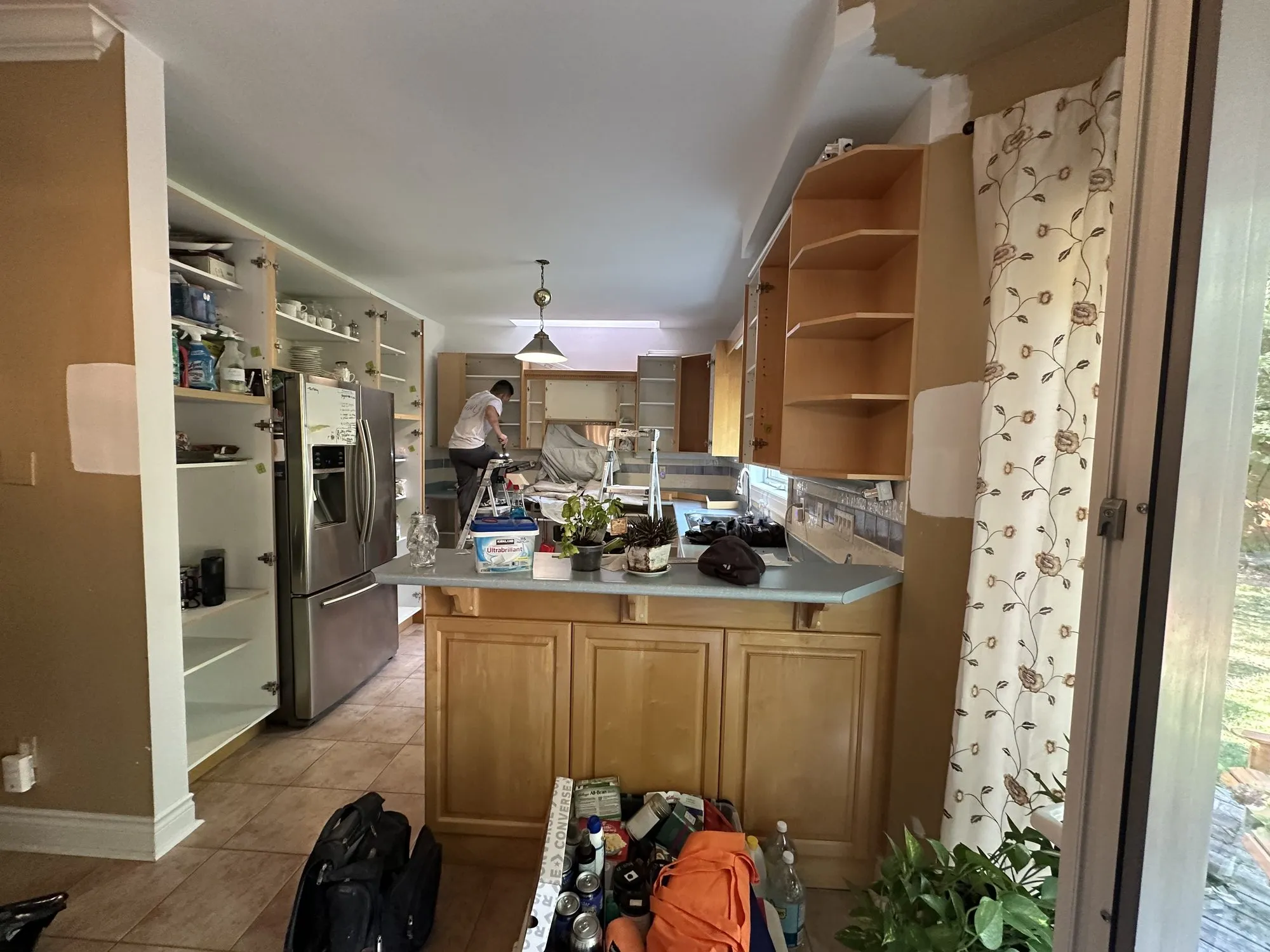 The kitchen mid-job with the old crown moulding stripped off, cabinet doors removed and the bare wall showing above the uppers