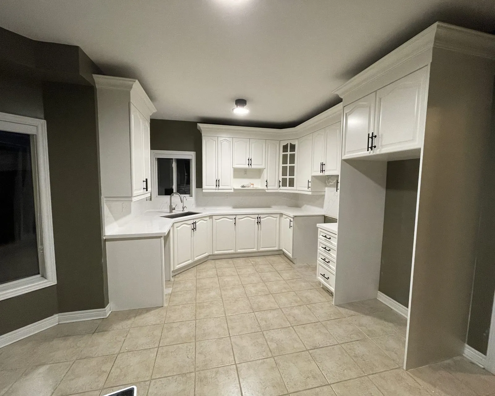 After — honey oak sprayed white, double crown and new handles, counters and backsplash by others in Wedgewood Creek, Oakville