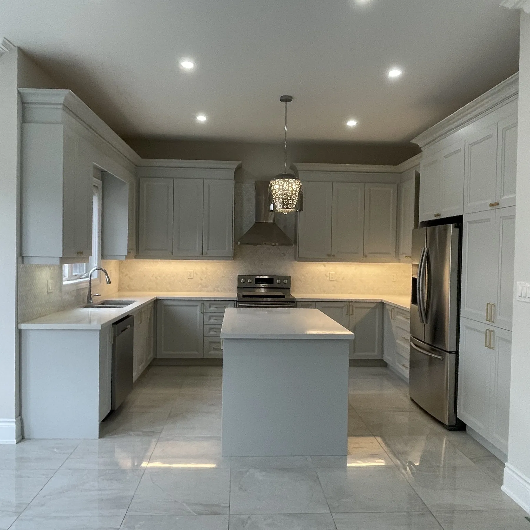 After — A Glen Abbey kitchen before and after refacing — grey slab doors replaced with soft-grey shaker fronts and crown moulding, on the original cabinet boxes