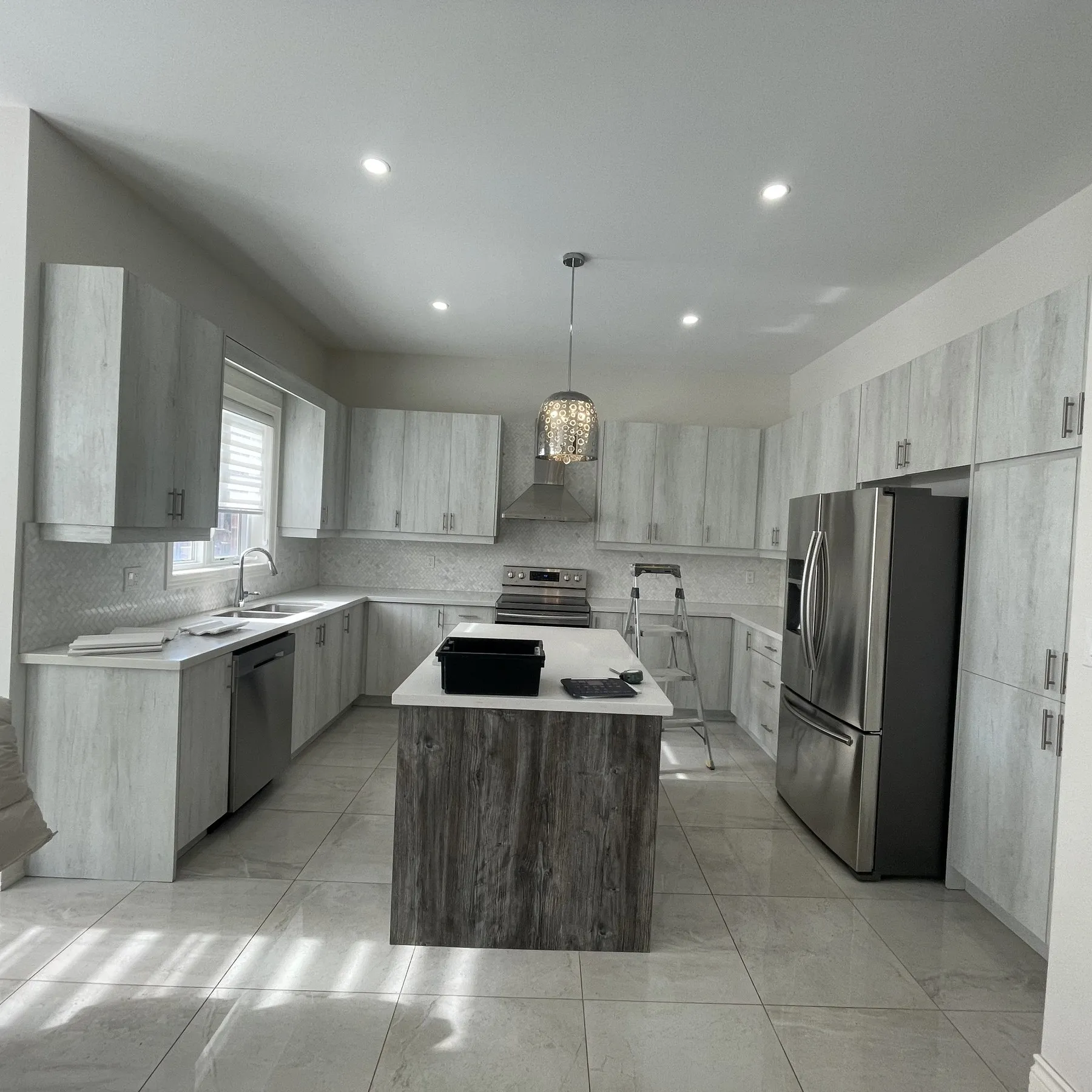 Before — A Glen Abbey kitchen before and after refacing — grey slab doors replaced with soft-grey shaker fronts and crown moulding, on the original cabinet boxes