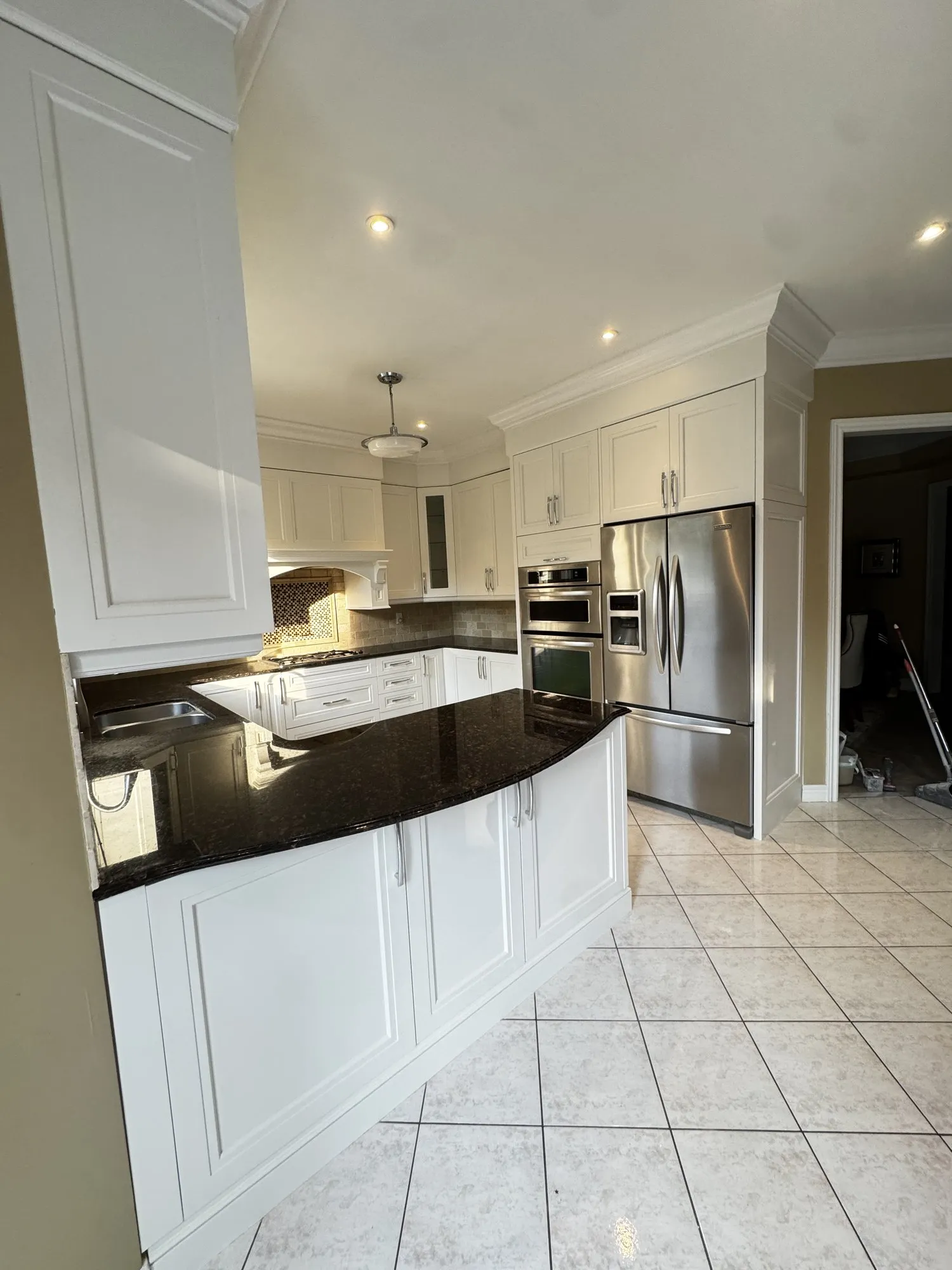 The finished kitchen with cream uppers and lowers on a single colour, dark granite counters and the original tile floor unchanged