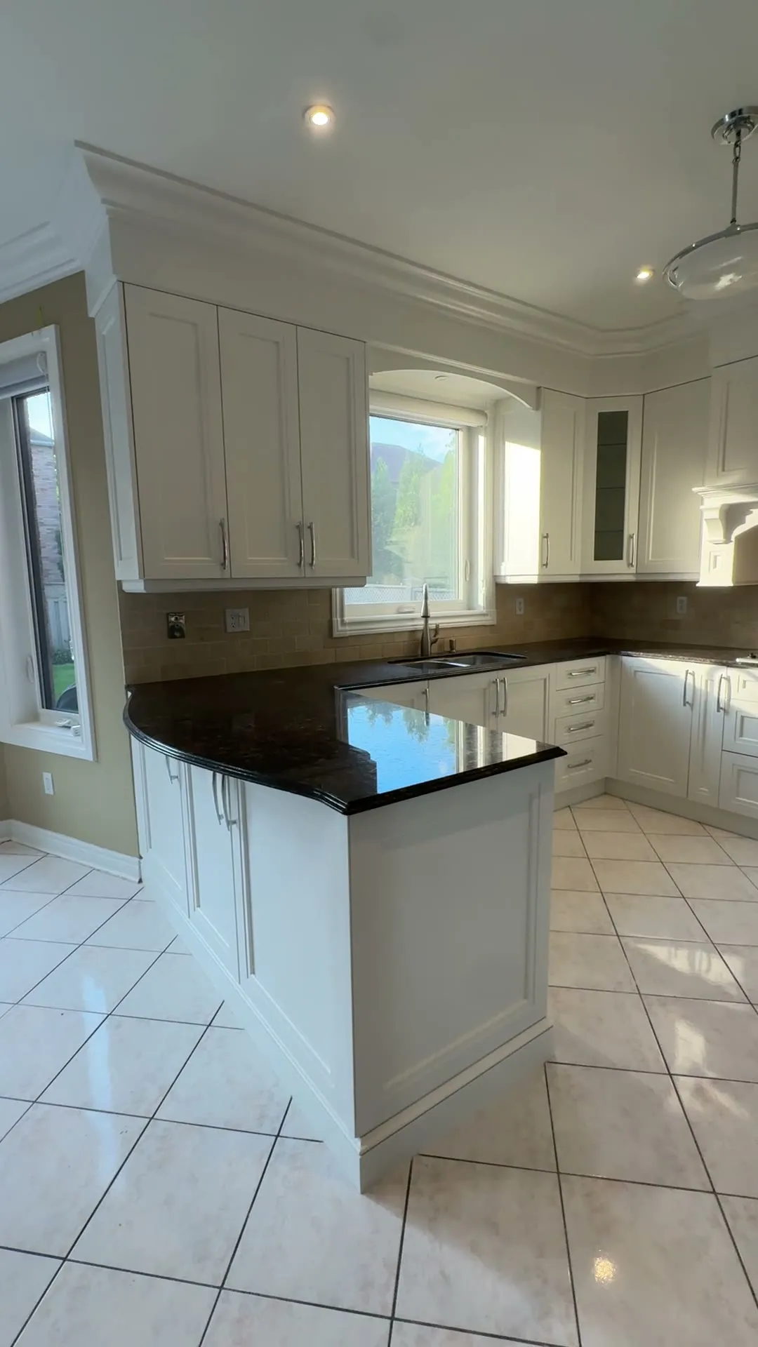 The finished Joshua Creek kitchen — cream doors above and below on one colour, the dark granite counters and tile floor kept, polished chrome pulls throughout