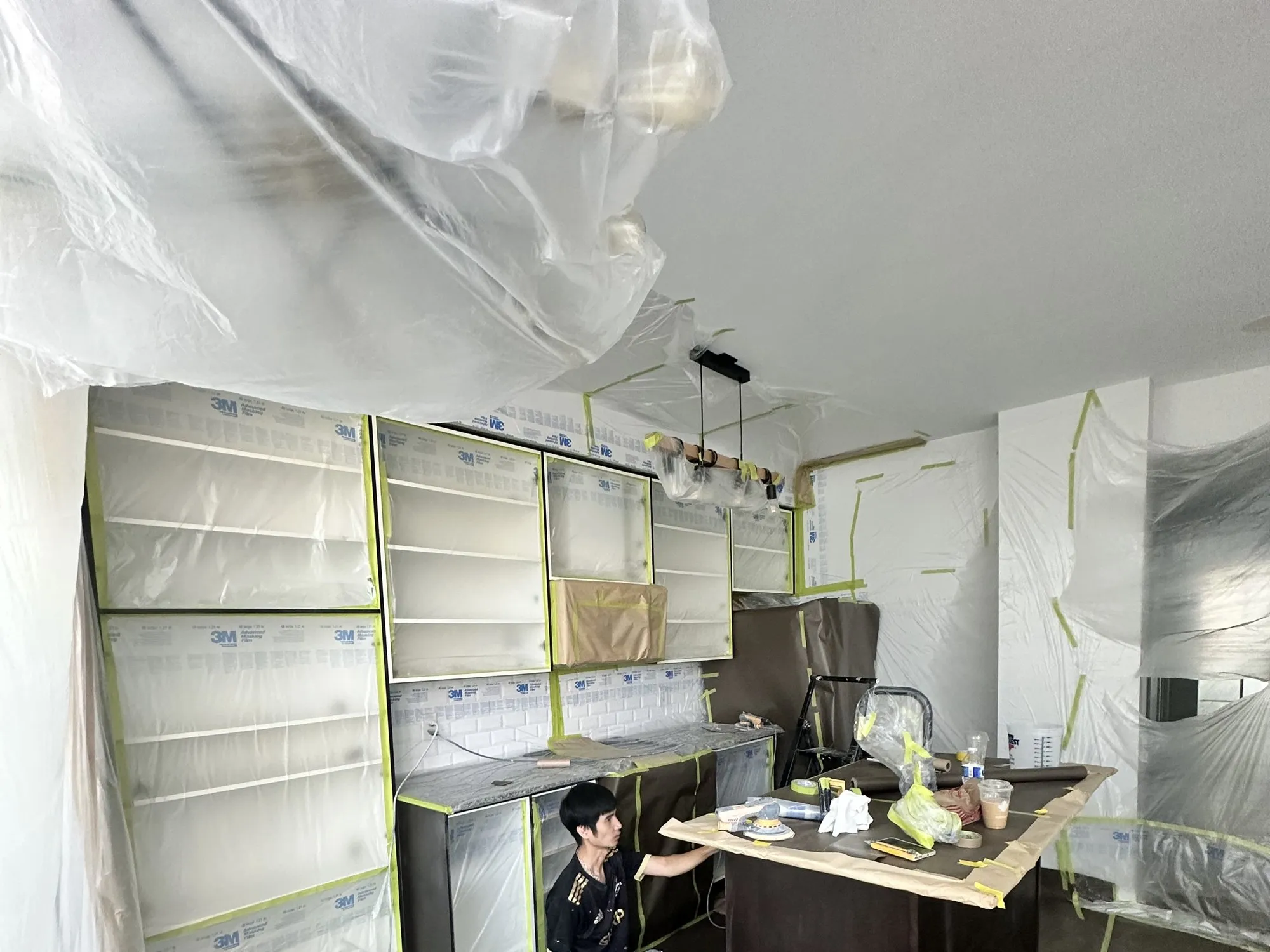 Cabinet boxes, walls and ceiling sealed behind sheeting and tape before any spraying starts