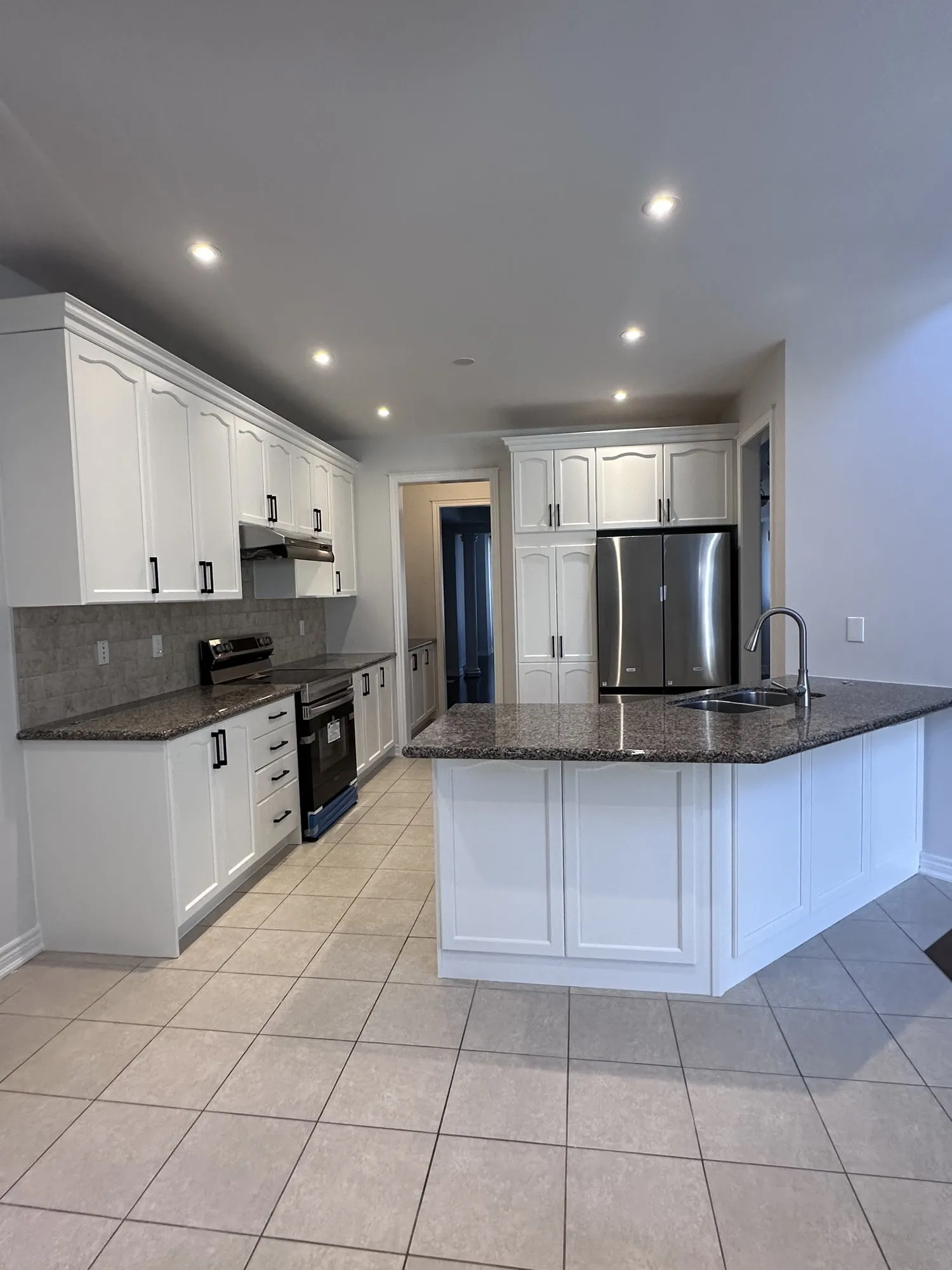 After — cherry-stained cabinets sprayed white, 32 new handles, granite kept — Glenorchy, Oakville