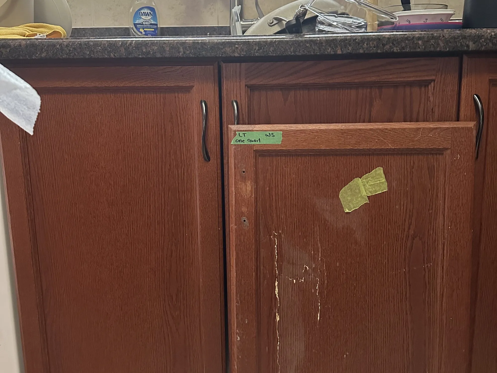 A cabinet door taken off and labelled, the old finish streaked and worn through