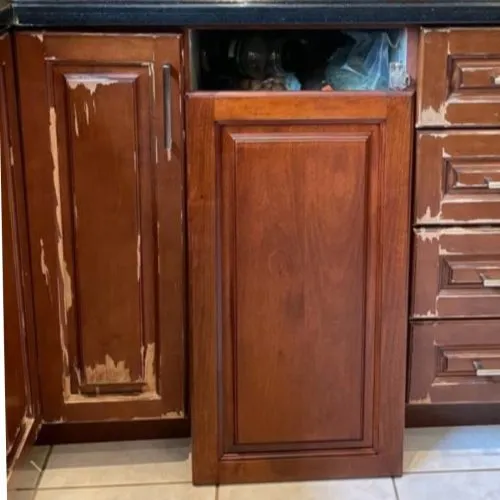 Cabinet doors with the old finish worn through, beside one stripped back and refinished