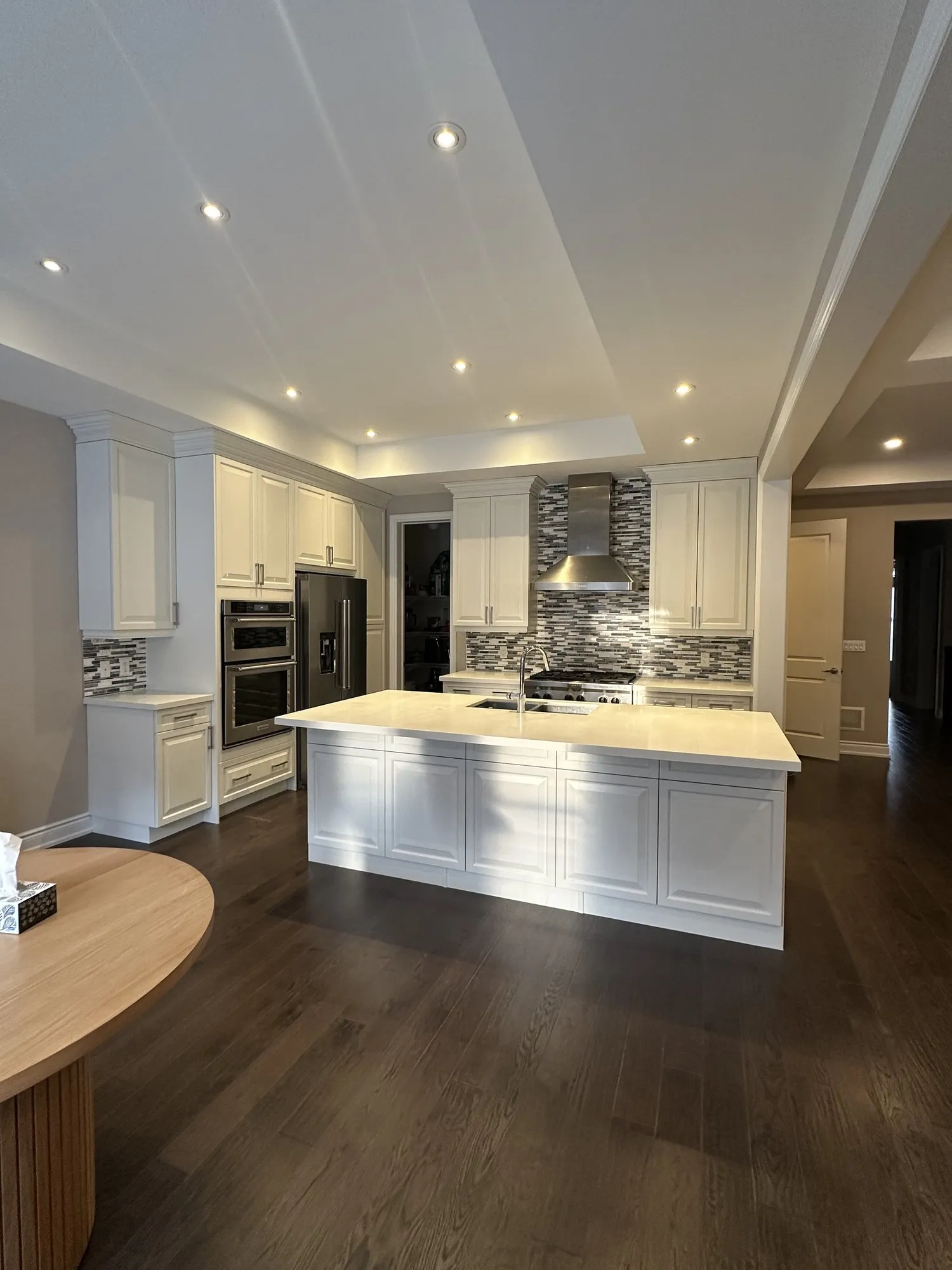 The finished kitchen in one tone of white, the island, range wall and mosaic backsplash all as they were but the cabinetry now light