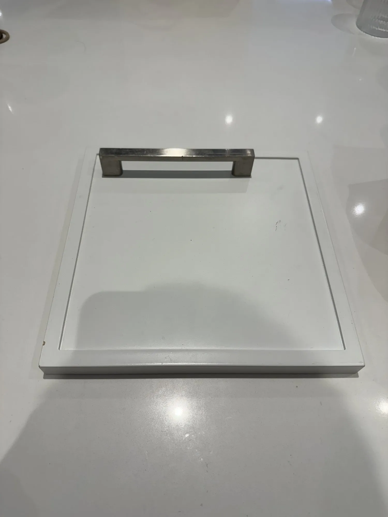 A single bar pull laid on the white quartz counter before the hardware was ordered