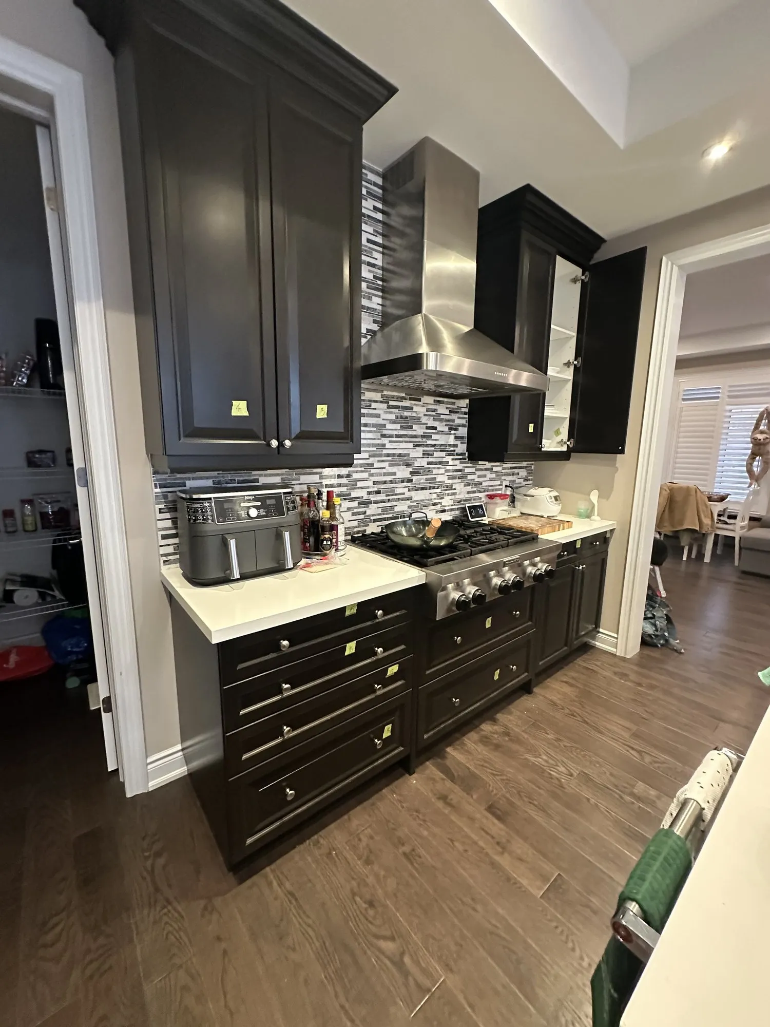 The range wall before the work, dark espresso cabinetry above and below a white quartz counter and a glass mosaic backsplash
