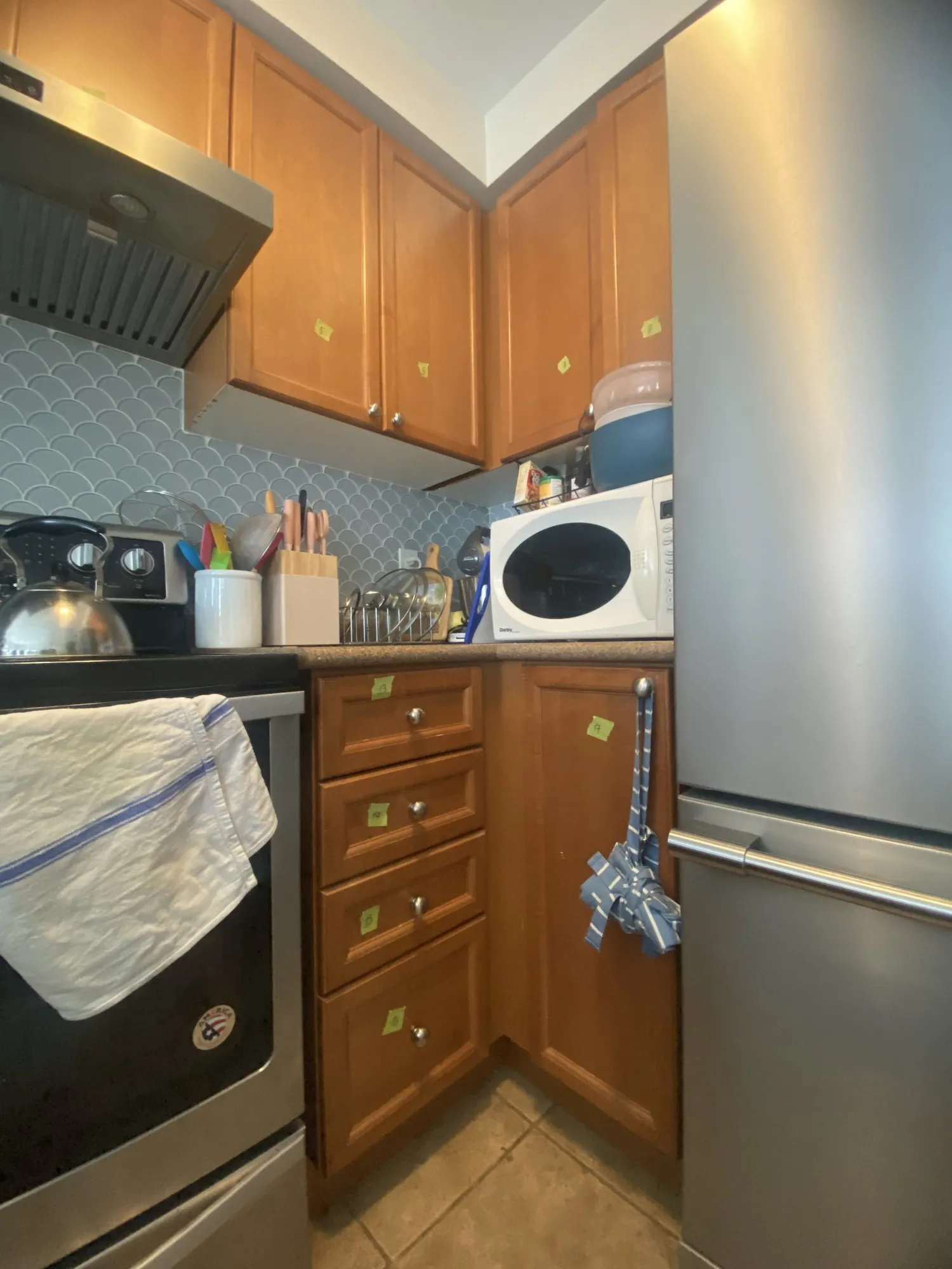 The original honey oak cabinetry with beige laminate counters and a patterned tile backsplash