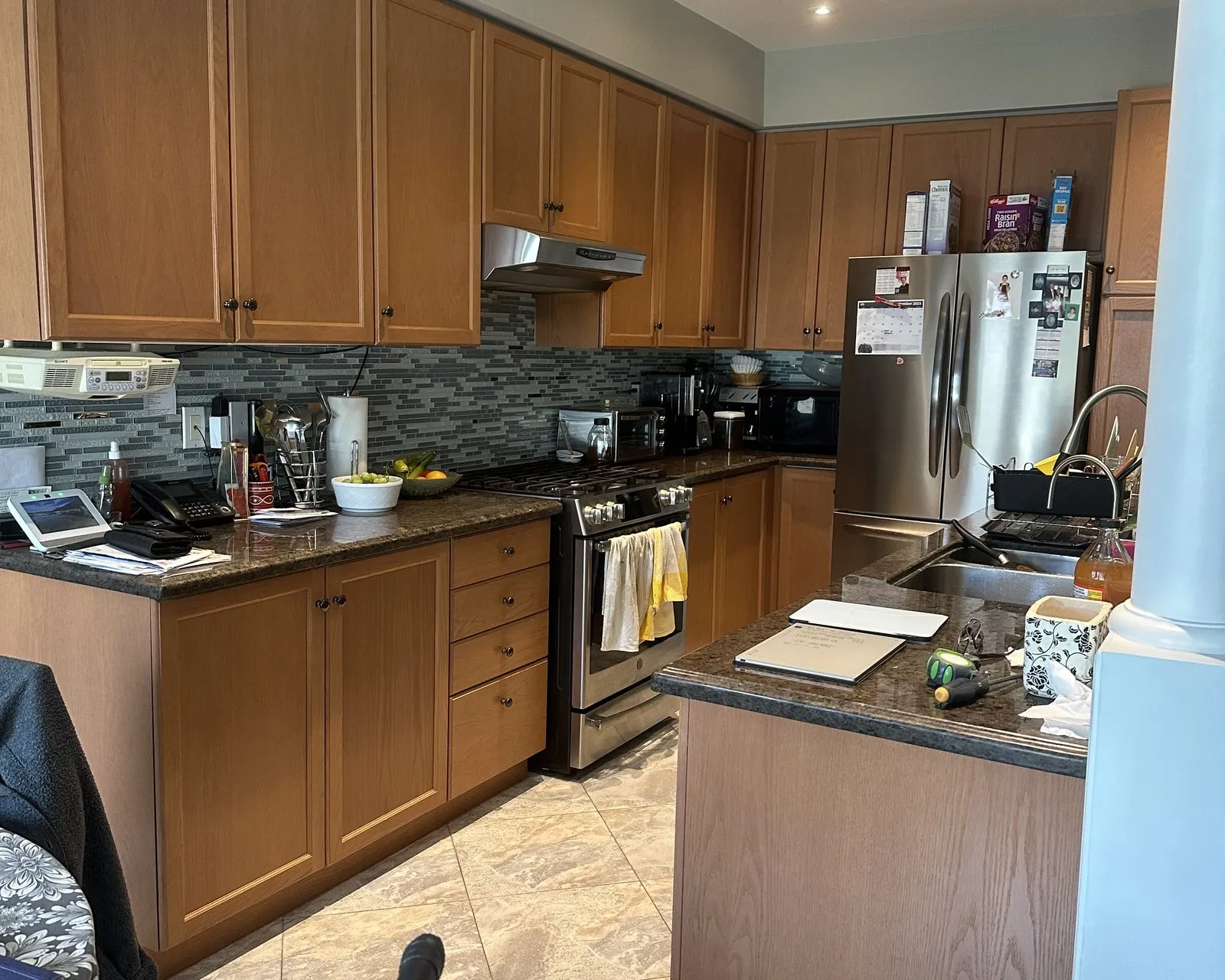 Before — Quartz countertop replacement in Oak Park, Oakville — dark granite on oak cabinetry replaced with Calacatta-look quartz, carried up the wall as a slab backsplash