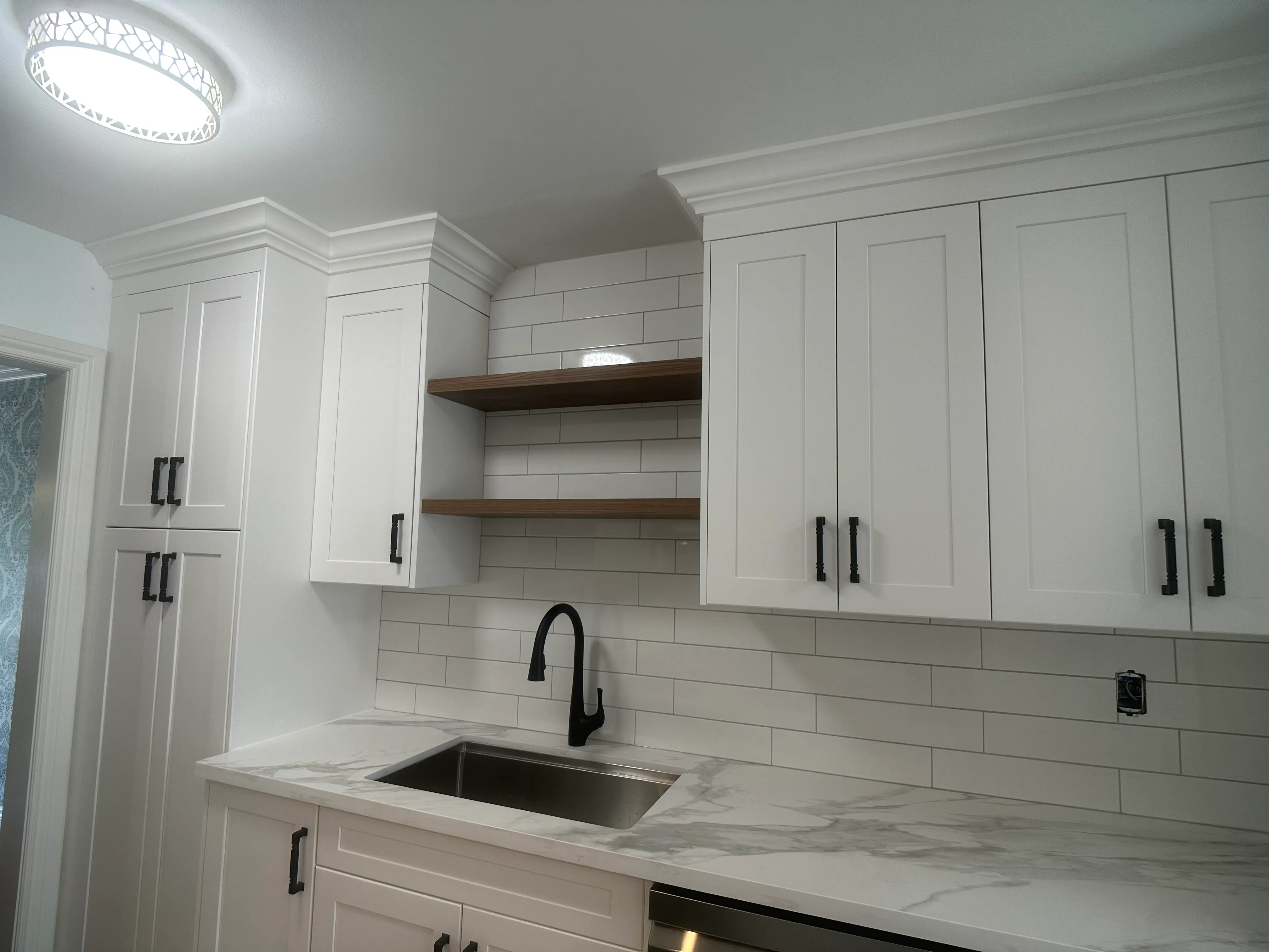 A quartz counter with soft grey veining at a sink and black faucet, white subway tile backsplash behind it