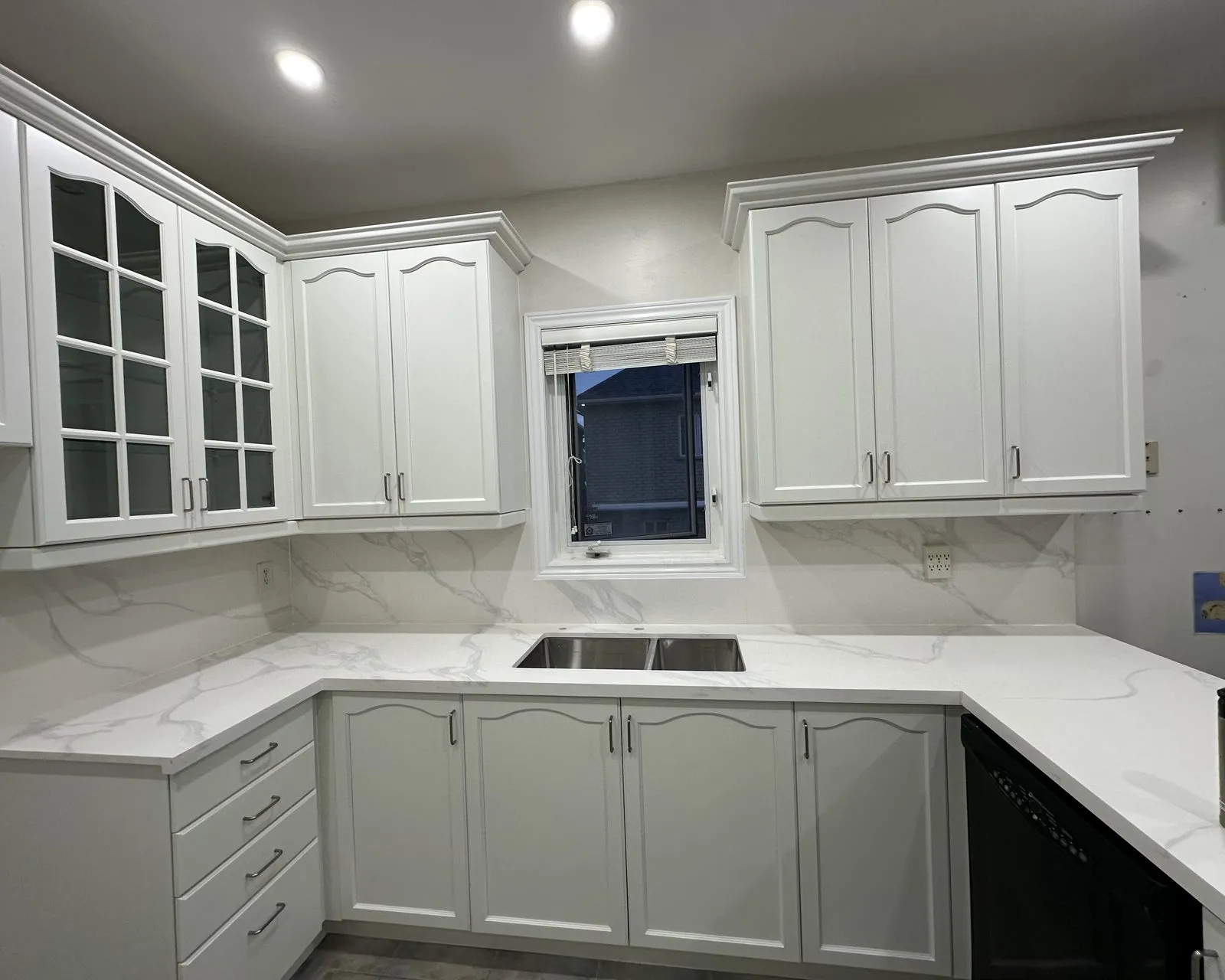 A quartz slab backsplash run full height behind the counter in an Oakville kitchen, the veining carried up the wall from the worktop
