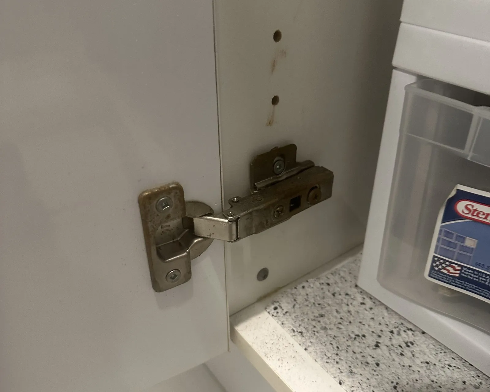 After — Soft-close hinge upgrade in Bronte Creek, Oakville — the original worn hinge in the cabinet frame, then the soft-close hinge fitted in the same holes