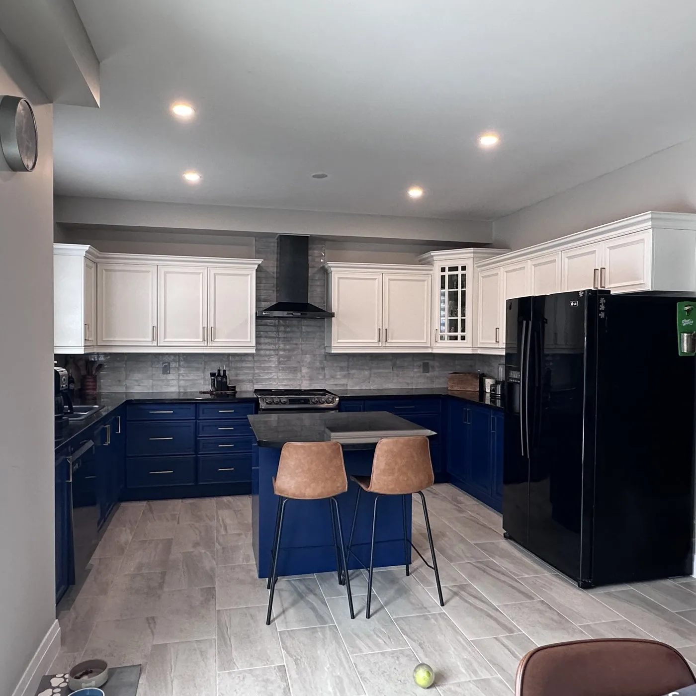 After — Spray painting in Oakville — oak cabinetry sprayed white above and navy below, with a new hood and backsplash