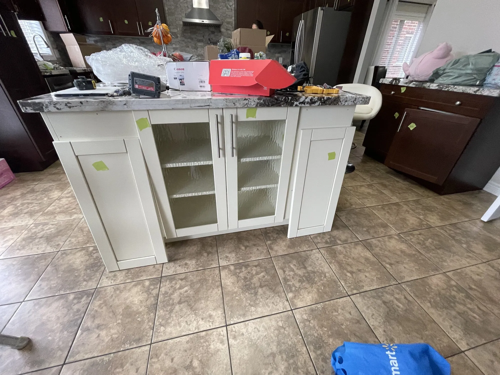 The original island, painted white with glass-fronted doors, standing against the dark espresso perimeter cabinetry behind it